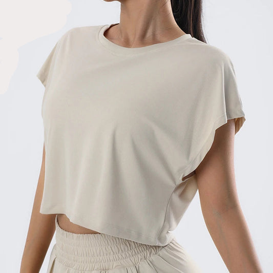 A woman wearing a beige short-sleeve cropped yoga top and matching skirt, with the brand name 'PEELI' visible on the top.