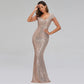 A woman modeling a floor-length, bodycon mermaid gown covered in shimmering rose-gold sequins, with short sheer embellished sleeves, against a light gray studio background.